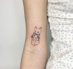 a small tattoo on the arm of a woman's left arm, with a cat holding a teddy bear