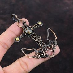 a hand holding a silver and gold colored metal skeleton pendant on it's finger