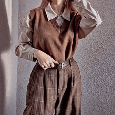 a young woman is posing for the camera wearing a sweater and wide legged pants with her hands on her head