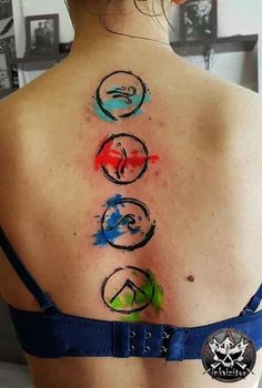 the back of a woman's shoulder with four symbols painted on her upper part