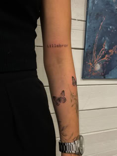 a woman with a butterfly tattoo on her arm and the word lillies written in cursive ink