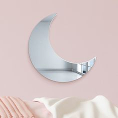 a mirror on the wall next to a bed with pink sheets and pillows in front of it