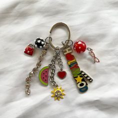 a key chain with various charms attached to it on a white sheeted surface,