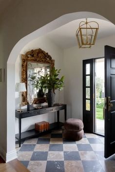 an entry way with a black door and checkered tile flooring in front of it