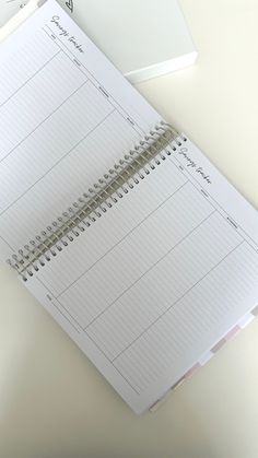 an open planner sitting on top of a desk next to a laptop