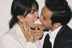 a man and woman kissing each other while eating cupcakes