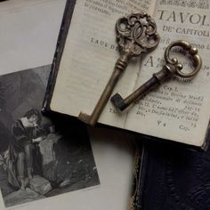 an old key is sitting on top of an open book