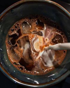 a bowl filled with liquid and ice on top of a table