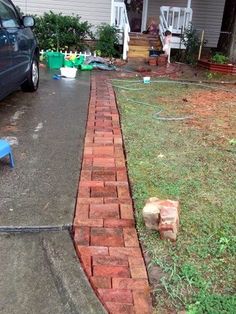 a blue car parked in front of a house next to a brick walkway and lawn