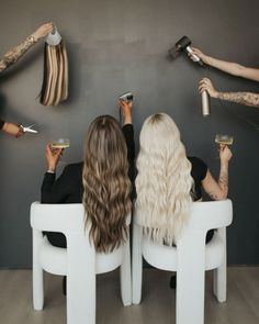 two women sitting in chairs with hair dryers and combs