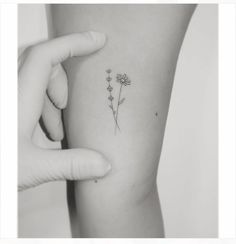 a woman's arm with a small flower tattoo on the left side of her arm