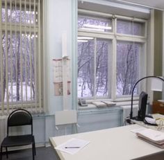 an office with desks and chairs in front of two large windows that have snow covered trees outside