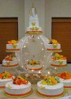 a table topped with lots of white cakes covered in frosting and orange flowers on top of each cake