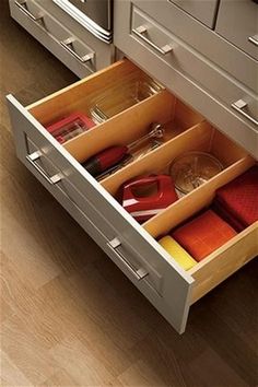 an open drawer in a kitchen with utensils and other items on the drawers