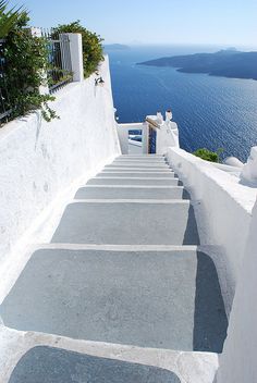 stairs leading up to the top of a building with blue water in the back ground