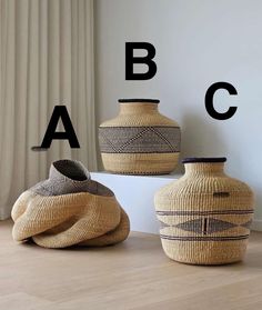 three vases sitting on top of a wooden floor next to each other with letters above them