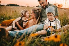 a man sitting on the ground with two children and an adult next to him in a field