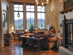 a living room filled with furniture and a fire place in front of two large windows