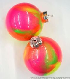 two christmas ornaments are sitting next to each other on a white surface, one is pink and the other is green