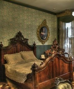 an old fashioned bedroom with green wallpaper and antique furniture, including a large bed