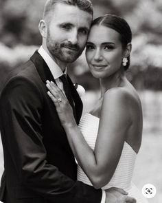 black and white photograph of a bride and groom hugging each other in front of trees