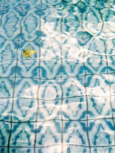 a yellow leaf floating on top of a blue swimming pool with water ripples around it