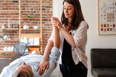 a woman getting her leg examined by a chiropist in a room with brick walls