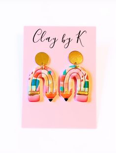 a pair of pink and yellow earrings on top of a pink card with the words clay by k