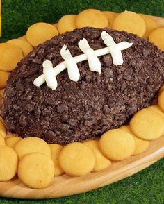 a football cake on a platter with cookies