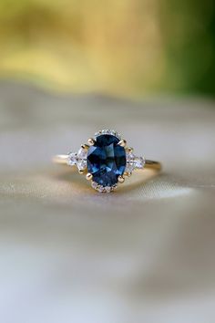 Classic twist on Princess Diana engagement ring with oval blue sapphire and diamonds in 14k yellow gold. The ring features a 2ct (6.5x8.5mm) oval royal blue sapphire with teal overtone, eye clean.  The color is deep blue, really sparkling! The sapphire displays some color change under certain lightening - very intriguing and unique.  The setting is 14k yellow gold, SI/H diamonds, TDW 0.3ct. Partial halo, 2 marquise diamonds, and 2 round diamonds. The ring is ready to ship, it comes in a beautifu Oval Blue Sapphire Engagement Ring, Sapphire Engagement Ring And Wedding Band, Teal Sapphire Engagement Rings, Oval Engagement Ring Sapphire, Blue Oval Engagement Ring, Vintage Sapphire Engagement Rings, Sapphire Accent Engagement Ring, Sapphire Engagement Ring Cushion, Sapphire Gold Engagement Ring