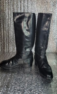 a pair of black boots sitting on top of a shiny surface