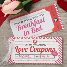 two valentine's day coupons sitting on top of a table next to flowers