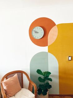 a room with a chair, clock and potted plant in front of the wall