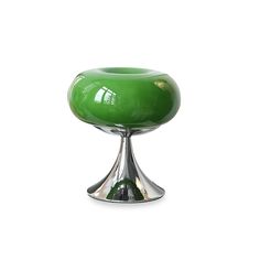 a green glass vase sitting on top of a metal stand in front of a white background