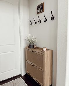 there is a wooden dresser with flowers on it in the corner next to a white door