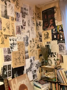 a room filled with lots of books and pictures on the wall next to a guitar