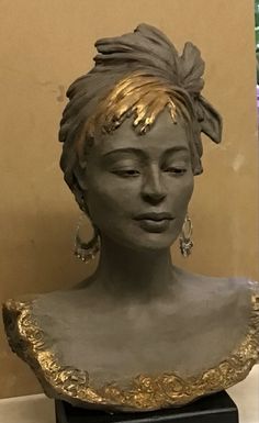 a statue of a woman with her eyes closed and gold hair in the middle of it's head