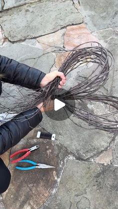 a woman sitting on top of a stone floor with scissors and wires in her hands