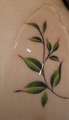 a woman's arm with green leaves painted on the back of her arm and shoulder