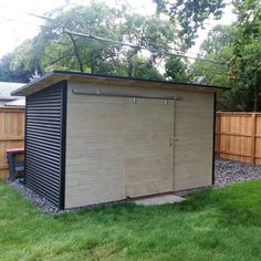 a small shed in the middle of a yard with grass around it and a wooden fence behind it