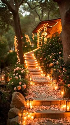 candles are lit on the steps leading up to a tree lined path with flowers and greenery