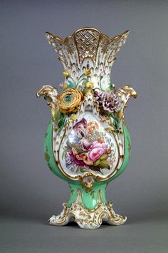 an ornate vase with flowers painted on the side and gold trimming around the base