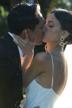 a man and woman kissing each other in front of trees