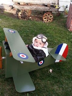 a small child in an airplane costume sitting on the grass