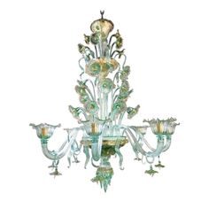 a green chandelier hanging from the ceiling with glass flowers and leaves on it