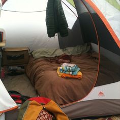 an open tent with clothes and blankets inside