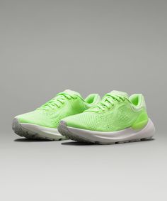 a pair of neon green sneakers on a gray background with white outs and grey soles