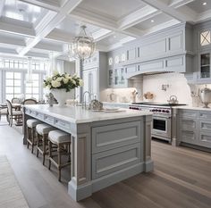 a large kitchen with gray cabinets and white counter tops, an island in the middle