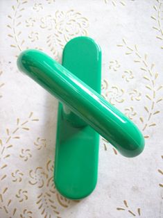 a green plastic object sitting on top of a white tablecloth with gold trimming