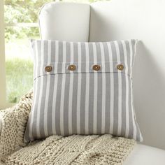 a white chair with a gray and white striped pillow